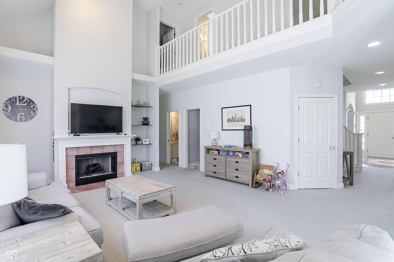 Bright two-story family room with fireplace and loft space.