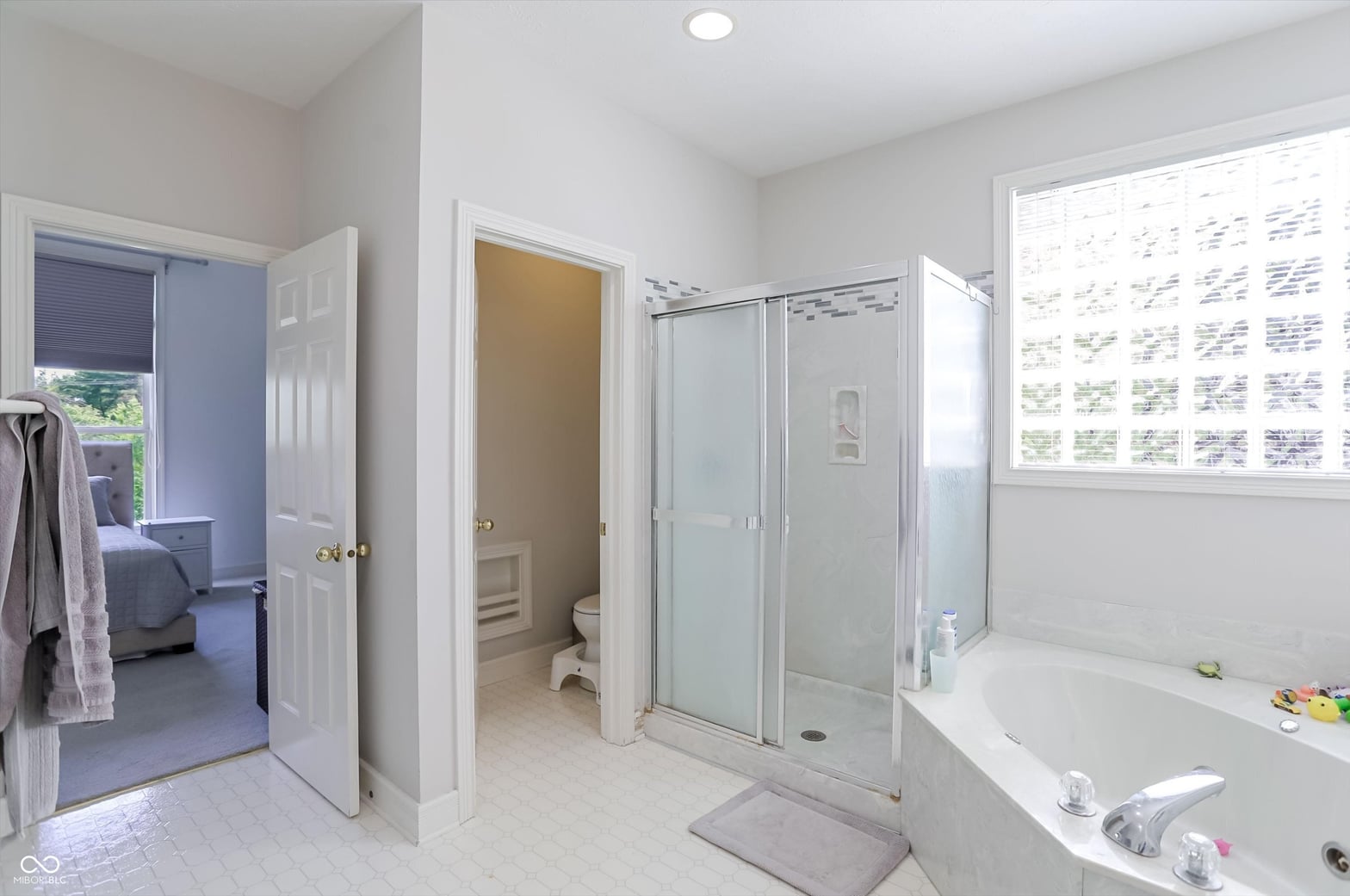 Spacious primary bath with luxurious shower and soaking tub.