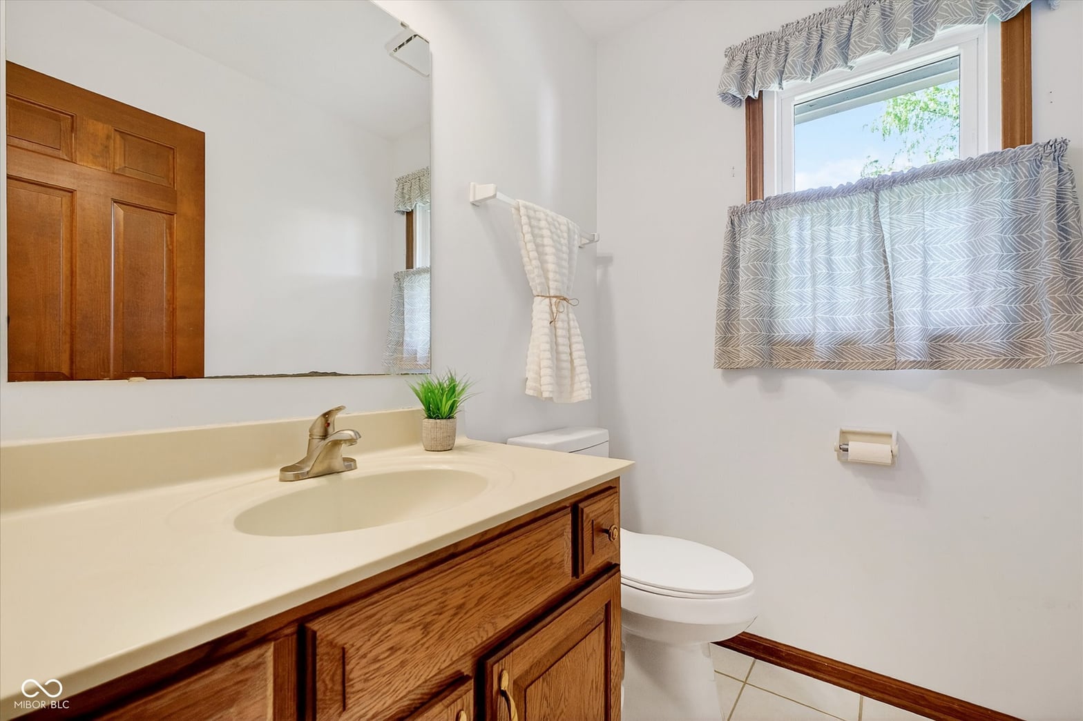 Bright primary bathroom with wood vanity and natural light.