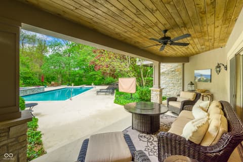 Outdoor living area at 7436 Glenvista Place, Fishers, IN — Resort-style covered patio overlooks sparkling pool.