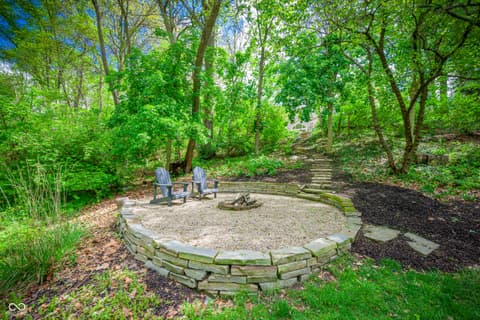 Outdoor living area at 7436 Glenvista Place, Fishers, IN — Private wooded fire pit area with mature trees and seating.