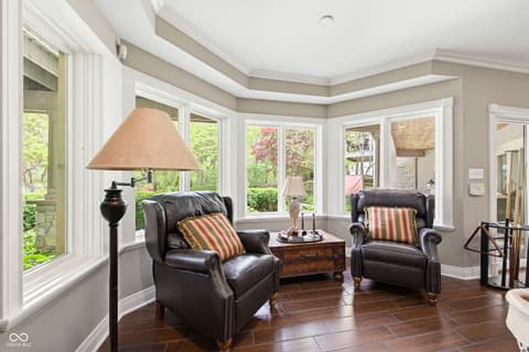 Living room at 7436 Glenvista Place, Fishers, IN — Elegant sunroom with curved ceiling and panoramic windows.