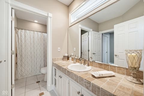 Primary bathroom at 7436 Glenvista Place, Fishers, IN — Spa-like primary bath with travertine counters and skylight.