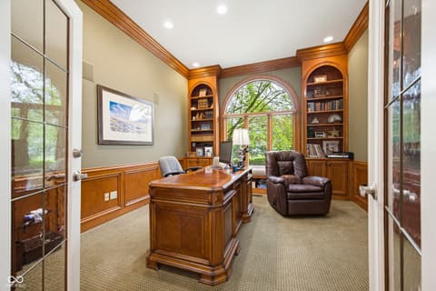 Home office at 7436 Glenvista Place, Fishers, IN — Elegant wood-paneled home office with built-in shelving.