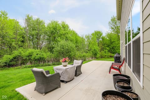 Outdoor living area at 17462 Cavalcade Circle, Noblesville, IN — Expansive patio with wooded backdrop and mature landscaping.