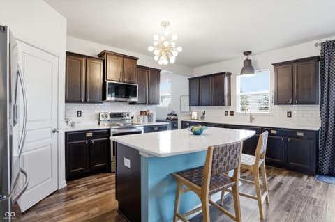 Kitchen at 14680 Hinton Drive, Fishers, IN — Modern kitchen with dark cabinetry and white quartz island.