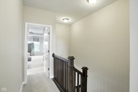 Hallway at 13311 Susser Way, Fishers, IN — Bright hallway with dark wood railings and modern lighting.