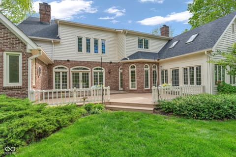 Backyard at 3172 Smokey Ridge Lane, Carmel, IN — Expansive brick home with elegant deck and landscaping.