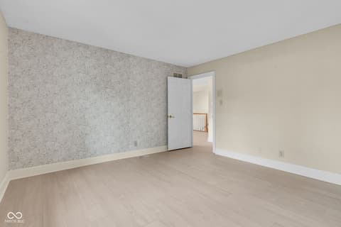 Bedroom at 3172 Smokey Ridge Lane, Carmel, IN — Spacious bedroom with hardwood floors and accent wallpaper.