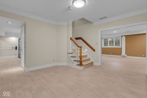 Basement at 3172 Smokey Ridge Lane, Carmel, IN — Spacious finished basement with elegant wood staircase.