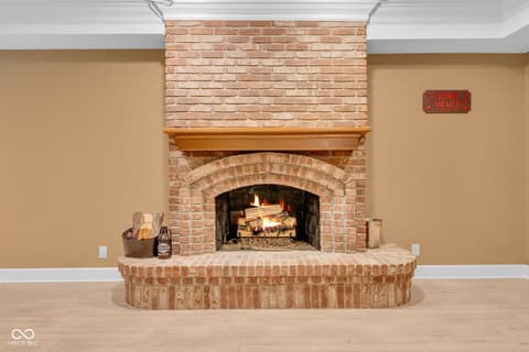 Family room at 3172 Smokey Ridge Lane, Carmel, IN — Classic brick fireplace with arched design and wood mantel.