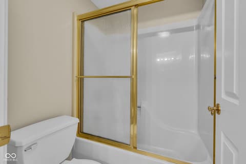 Primary bathroom at 3172 Smokey Ridge Lane, Carmel, IN — Spa-like bathroom with elegant gold-framed shower enclosure.