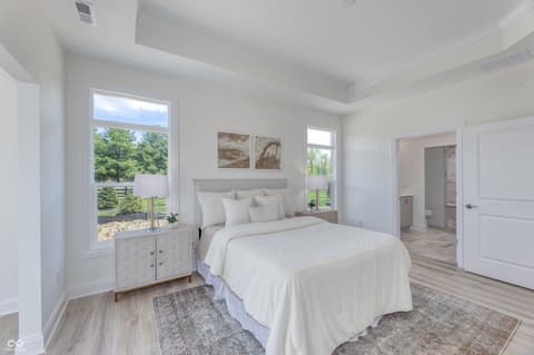 Primary bedroom at 16743 Sunland Farm Drive, Fishers, IN — Bright primary suite with tray ceiling and pastoral views.
