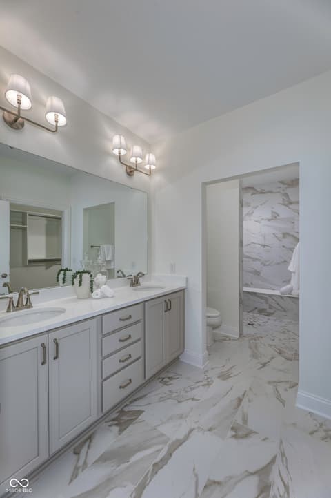 Primary bathroom at 16743 Sunland Farm Drive, Fishers, IN — Luxurious primary bath with marble finishes and dual vanity.