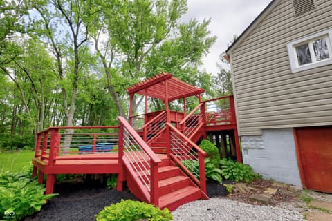 Outdoor living area at 11005 Cornell Street, Carmel, IN — Bold red modern deck with pergola and mature landscaping.