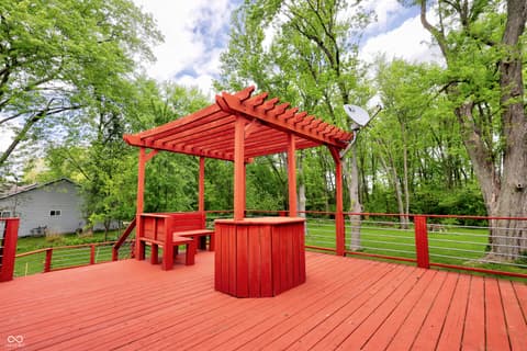 Outdoor living area at 11005 Cornell Street, Carmel, IN — Custom red deck with pergola and built-in bar area.