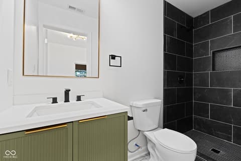 Primary bathroom at 1335 Christian Avenue, Noblesville, IN — Sleek primary bath with black tile shower and green vanity.