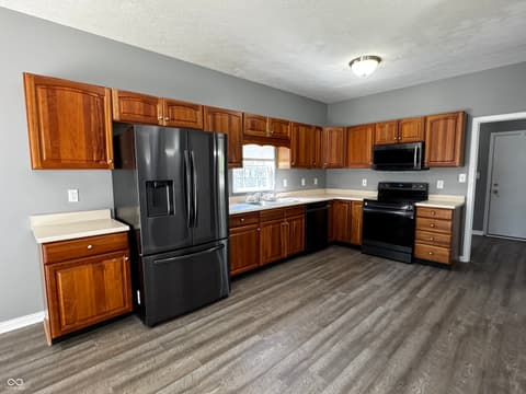 Kitchen at 13563 Guy Street, Fishers, IN — Updated kitchen with wood cabinets and black appliances.